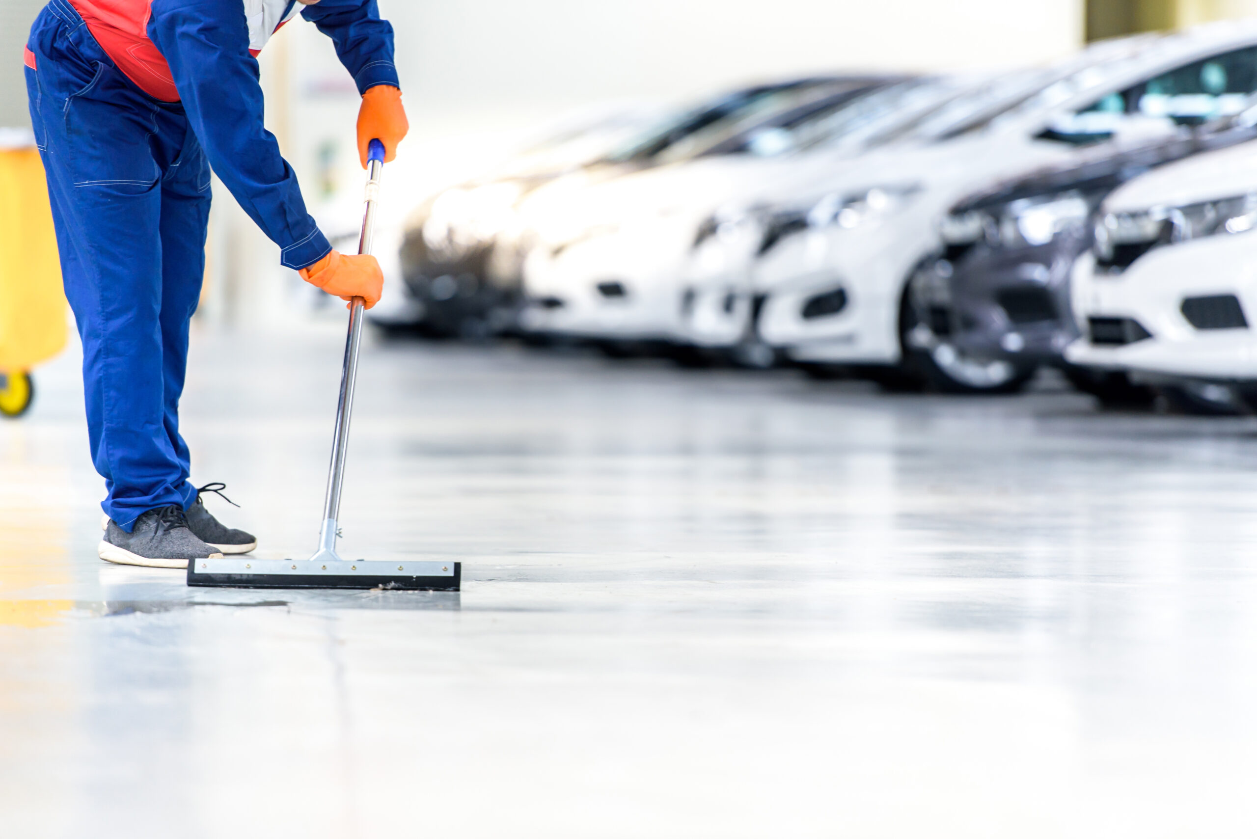 The car mechanic is cleaning, using a mop, rolling water from th